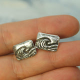 wave cufflinks on hand