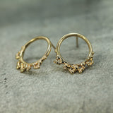 Gold hoop earrings with intricate designs on a gray surface