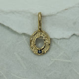 Gold pendant with a blue sapphire on a textured white background