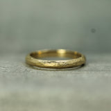 Gold ring with textured surface on a gray background