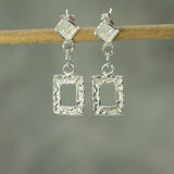 holding glimmer silver square earrings