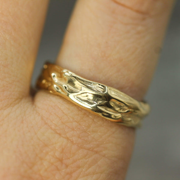 gold wedding band inspired by flowing tides of water on hand 