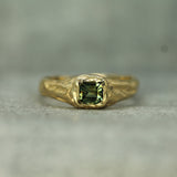 14k yellow gold signet ring with a green sapphire on a gray background