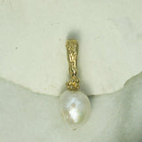 Gold pendant with a pearl on a textured surface