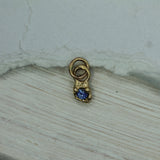 Gold charm with a blue gemstone on a light wooden surface