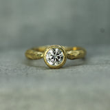 18k Yellow Gold ring with a diamond on a gray background