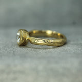 Gold ring with a diamond on a textured gray surface