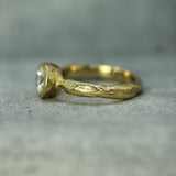 Gold ring with a diamond on a textured gray surface