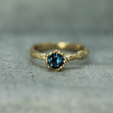 Gold ring with a blue sapphire on a textured gray background