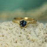 Gold ring with a blue sapphire on a textured surface