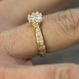 Gold ring with a diamond on a finger against a blurred background