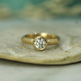 Gold ring with a diamond on a natural stone surface