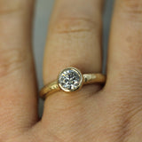 Gold engagement ring with a diamond on a person's finger