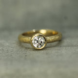 Gold ring with a lab-grown diamond on a gray surface