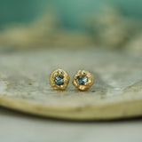 Gold earrings with blue sapphires on a natural stone surface