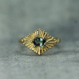 Gold ring with teal sapphires on a gray background