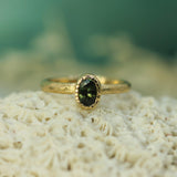 Gold ring with a green sapphire on a textured surface