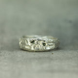 Silver ring with intricate design on a gray surface