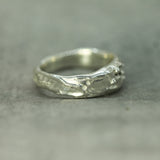 Silver ring with textured design on a gray background
