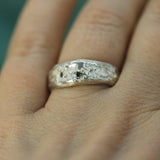Silver ring with small sapphires on a finger against a blurred background