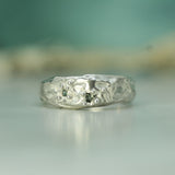 Silver ring with intricate designs on a blurred background