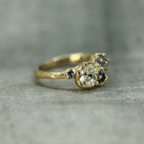 Gold ring with a central diamond and smaller stones on a gray background