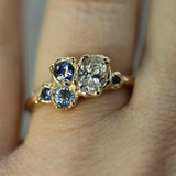 lab-grown oval diamond with blue sapphires in a cluster ring on hand