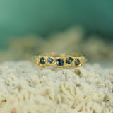 Gold ring with blue sapphries on a textured surface with a blurred natural background