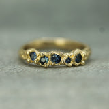 Gold ring with embedded blue sapphires on a textured surface
