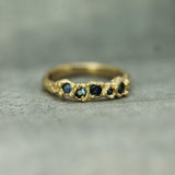 Gold ring with embedded blue sapphires on a textured surface