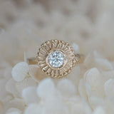 Handcarved sun beams surround a diamond in yellow gold