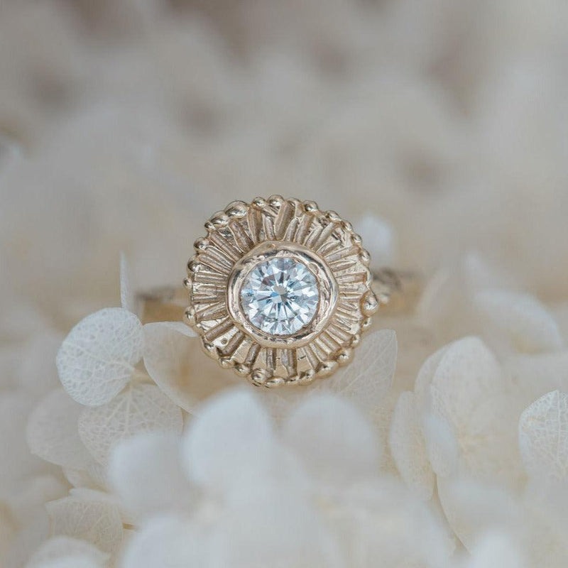 Handcarved sun beams surround a diamond in yellow gold 