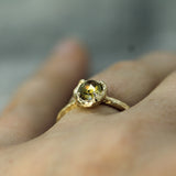 A close-up of a gold ring with a yellow rosecut sapphire worn on a person's finger.