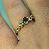 A close-up of a gold ring with a oval blue sapphire and four smaller sapphires, worn on a finger.