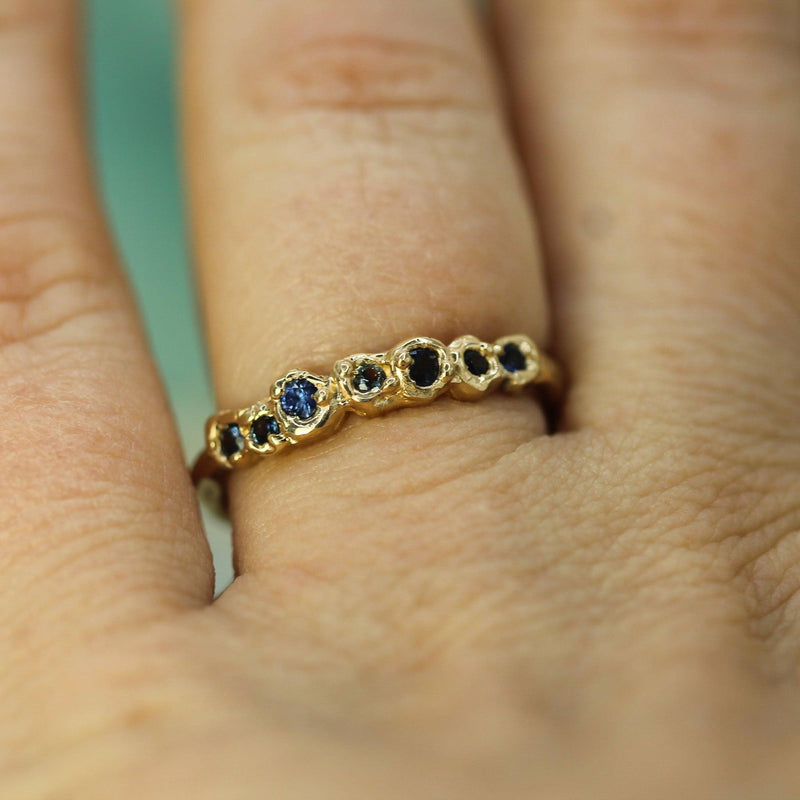 shown on hand with blue sapphires and yellow gold ring 