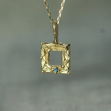 Gold pendant with a blue sapphire on a blurred background