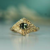 14k Gold ring with a teal sapphire on a blurred background