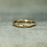 Gold ring with a textured design on a gray surface