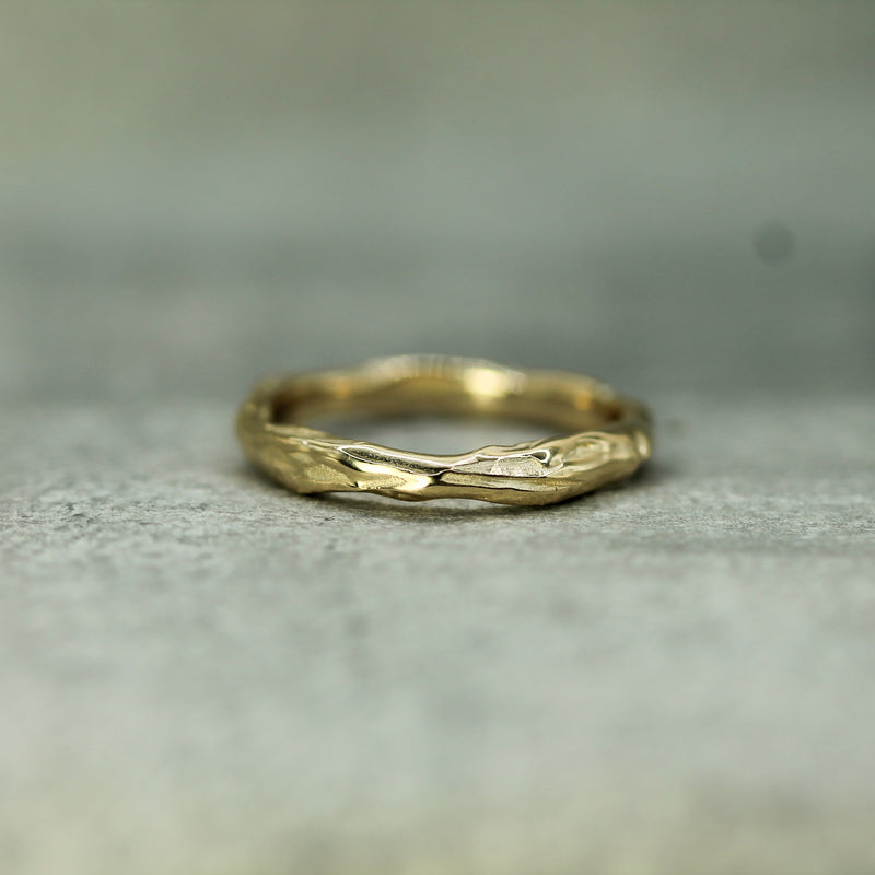 Gold ring with a textured design on a gray surface