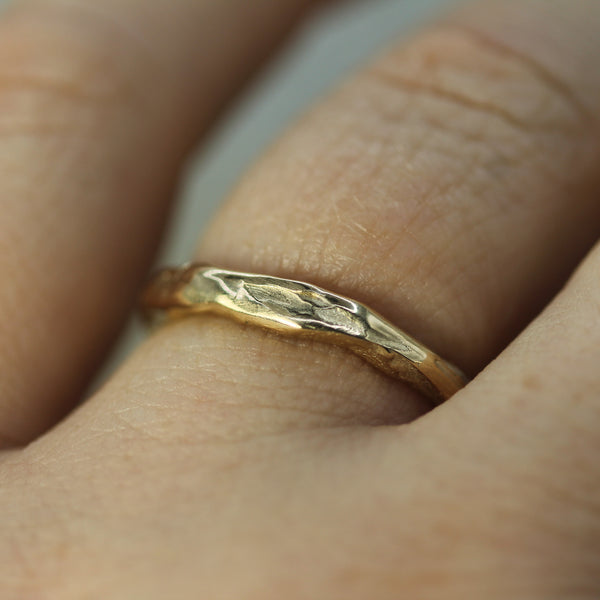 Gold ring with a textured band worn on a finger