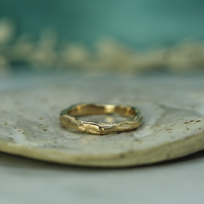 Gold ring on a textured stone surface with a blurred natural background