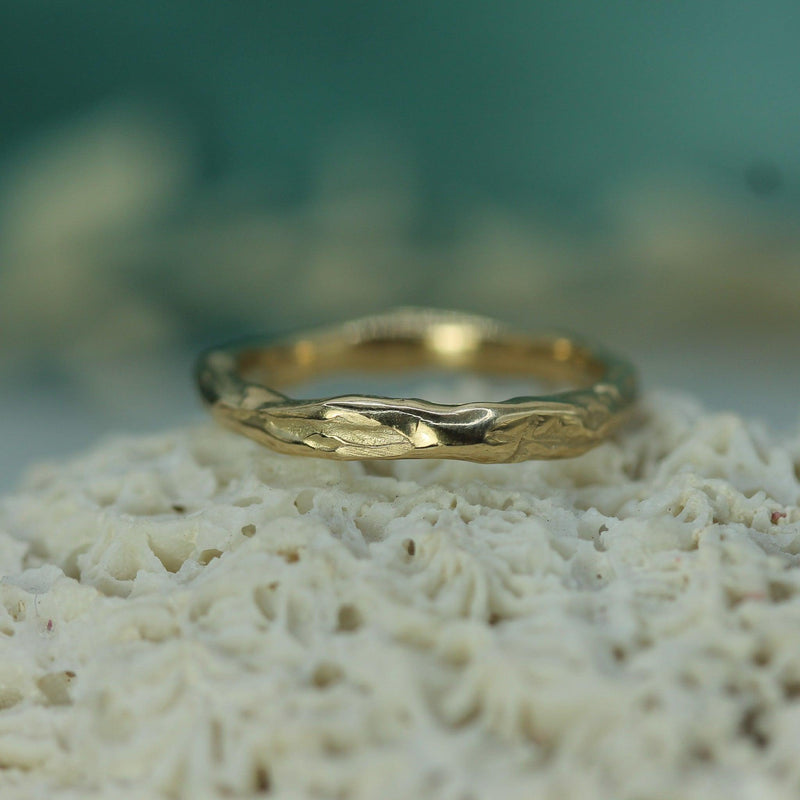 Gold ring on a textured surface with a blurred natural background