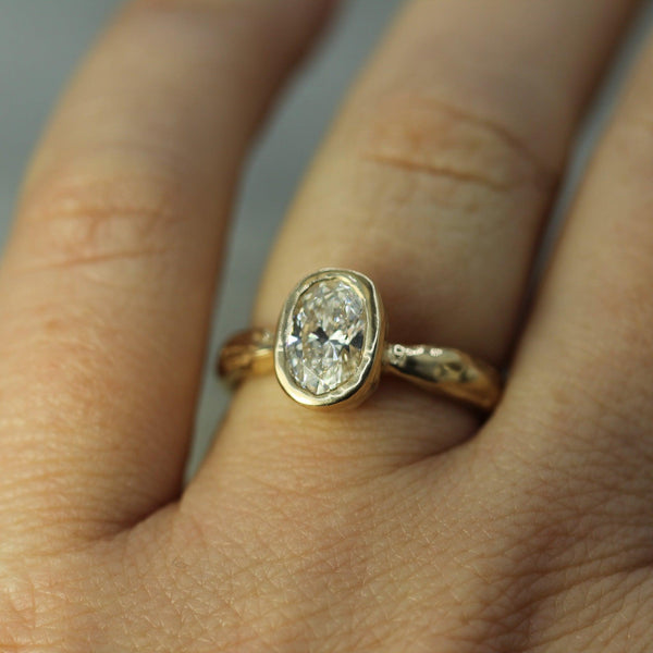 lab-grown diamond ring in yellow gold on a person's finger against a neutral background