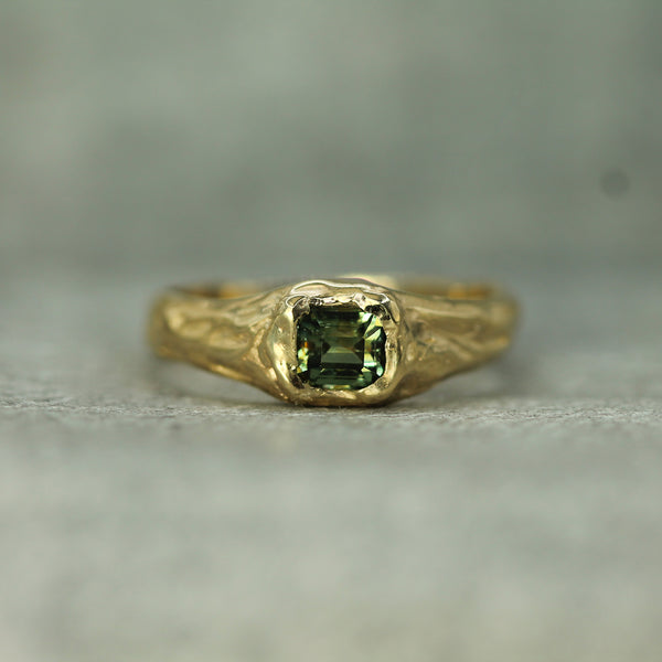 14k yellow gold signet ring with a green sapphire on a gray background
