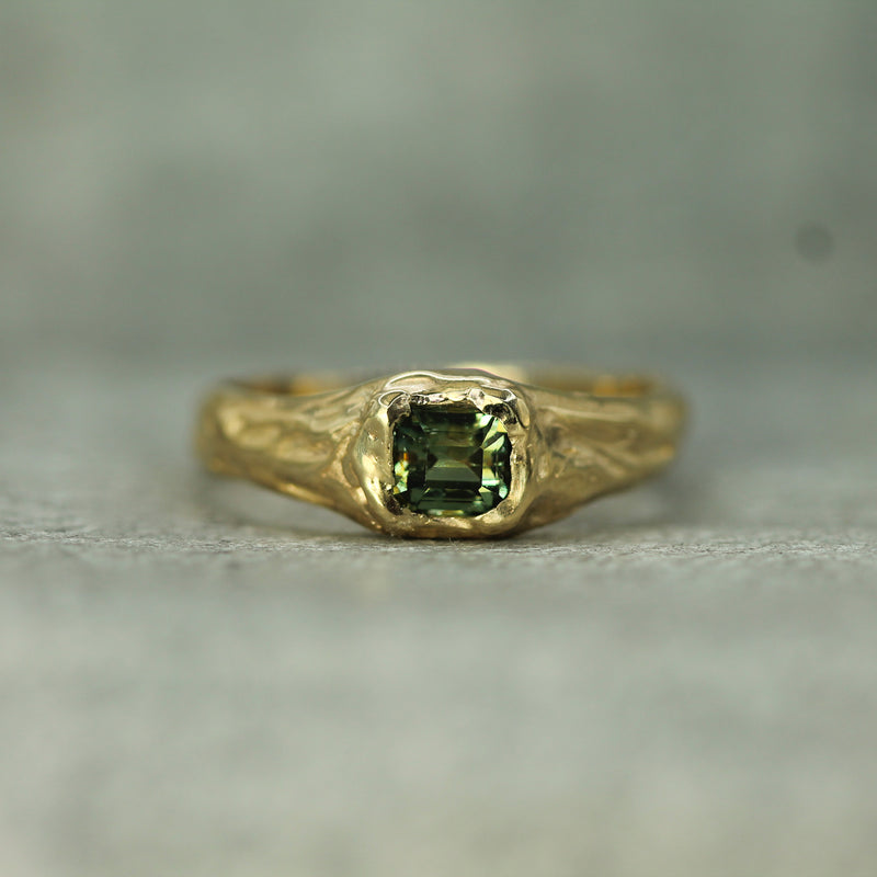 14k yellow gold signet ring with a green sapphire on a gray background