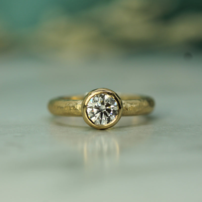 14k Yellow Gold ring with a diamond on a blurred background