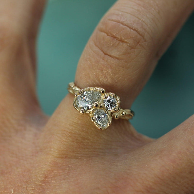 Gold ring with three diamonds on a finger against a blurred background
