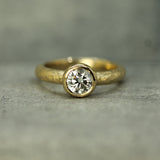 Gold ring with a  lab-grown diamond on a grey background