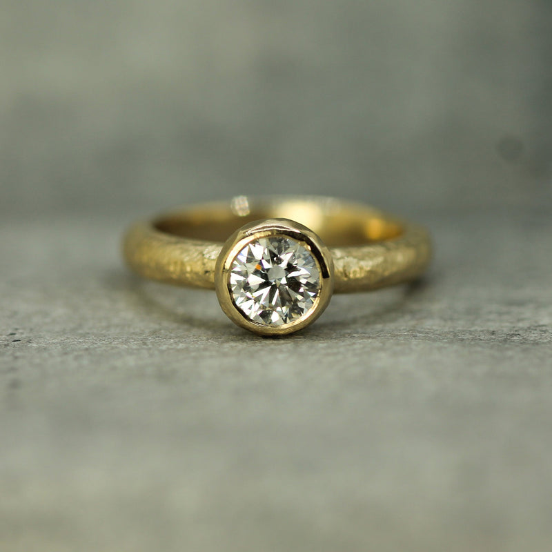 Gold ring with a  lab-grown diamond on a grey background