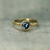 Gold ring with a blue sapphire on a textured surface